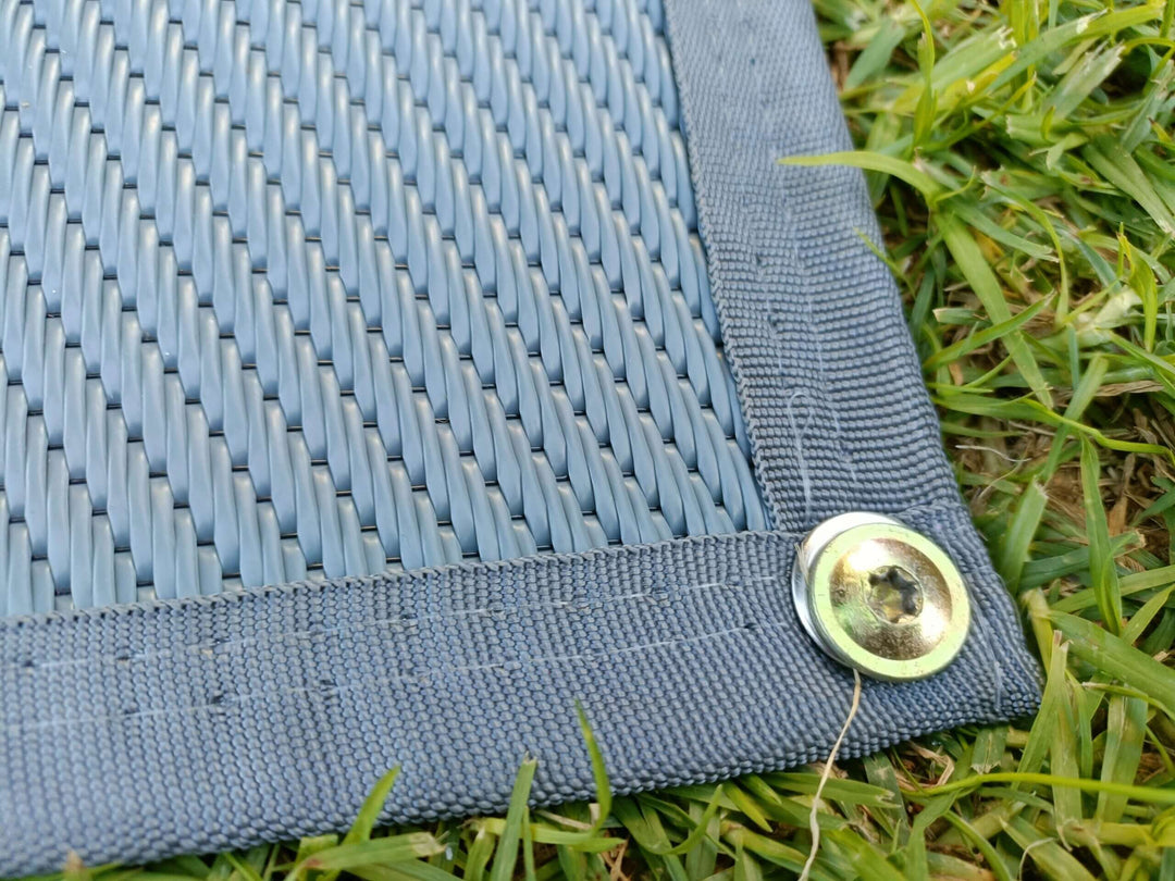 Close-up of the edge of a 6m x 2.4m recycled camping mat, showcasing quality material and durable grommet detail.