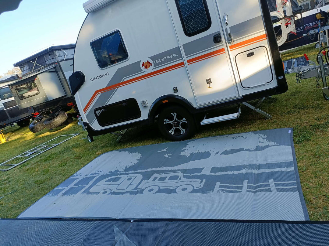 Recycled 6m x 2.4m camping mat laid out under a caravan, showcasing durability and style for outdoor setups.