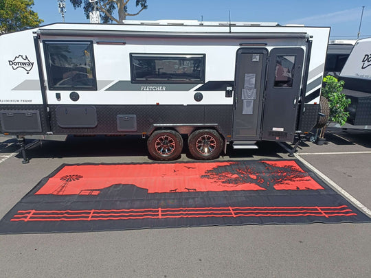 Spacious Country Orange recycled mat laid out under a camper trailer, showcasing its perfect fit for outdoor setups.