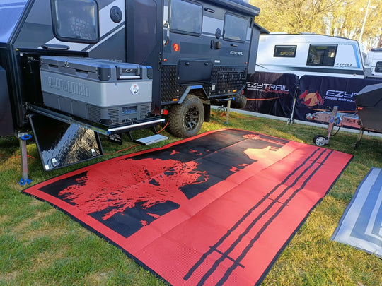 Red and black recycled poly camping mat laid out beside a camper van, ideal for outdoor adventures and DIY setups.