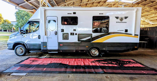 6m x 2.4m recycled camping mat laid out under a large camper van, showcasing its durability and ample space for outdoor comfort.