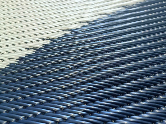 Close-up of a woven blue and white mat texture, showcasing durable recycled material for outdoor use.