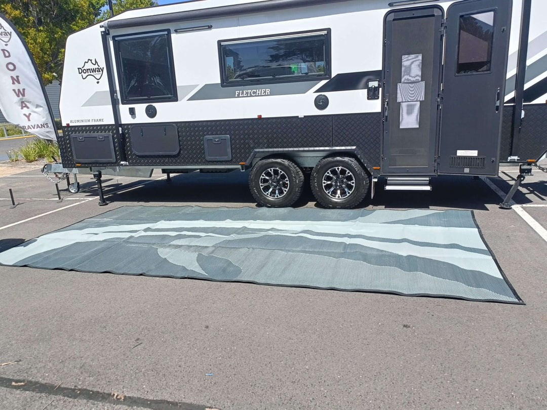 Swish Grey 5m x 2.4m recycled poly camping mat under a caravan, showcasing its durable and stylish design.