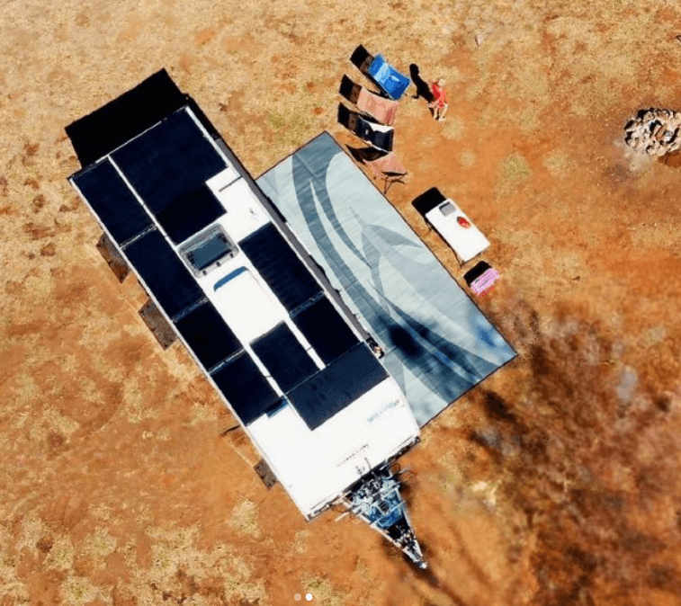 Aerial view of a camper setup on a Swish grey 6m x 2.4m recycled poly camping mat with chairs and solar panels.