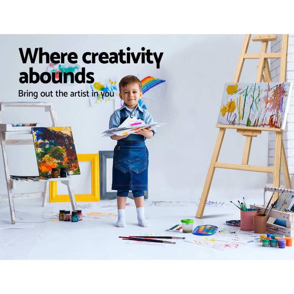 Child artist in denim apron at easel, showcasing creativity and joy in a colorful art studio.