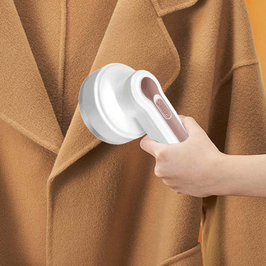 Hand holding GOMINIMO USB rechargeable fabric shaver on a brown coat, showcasing its efficient design and easy grip.