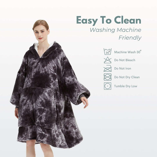 Woman wearing GOMINIMO Hoodie Blanket in tie-dyed grey, showcasing easy care instructions and machine wash friendly features.